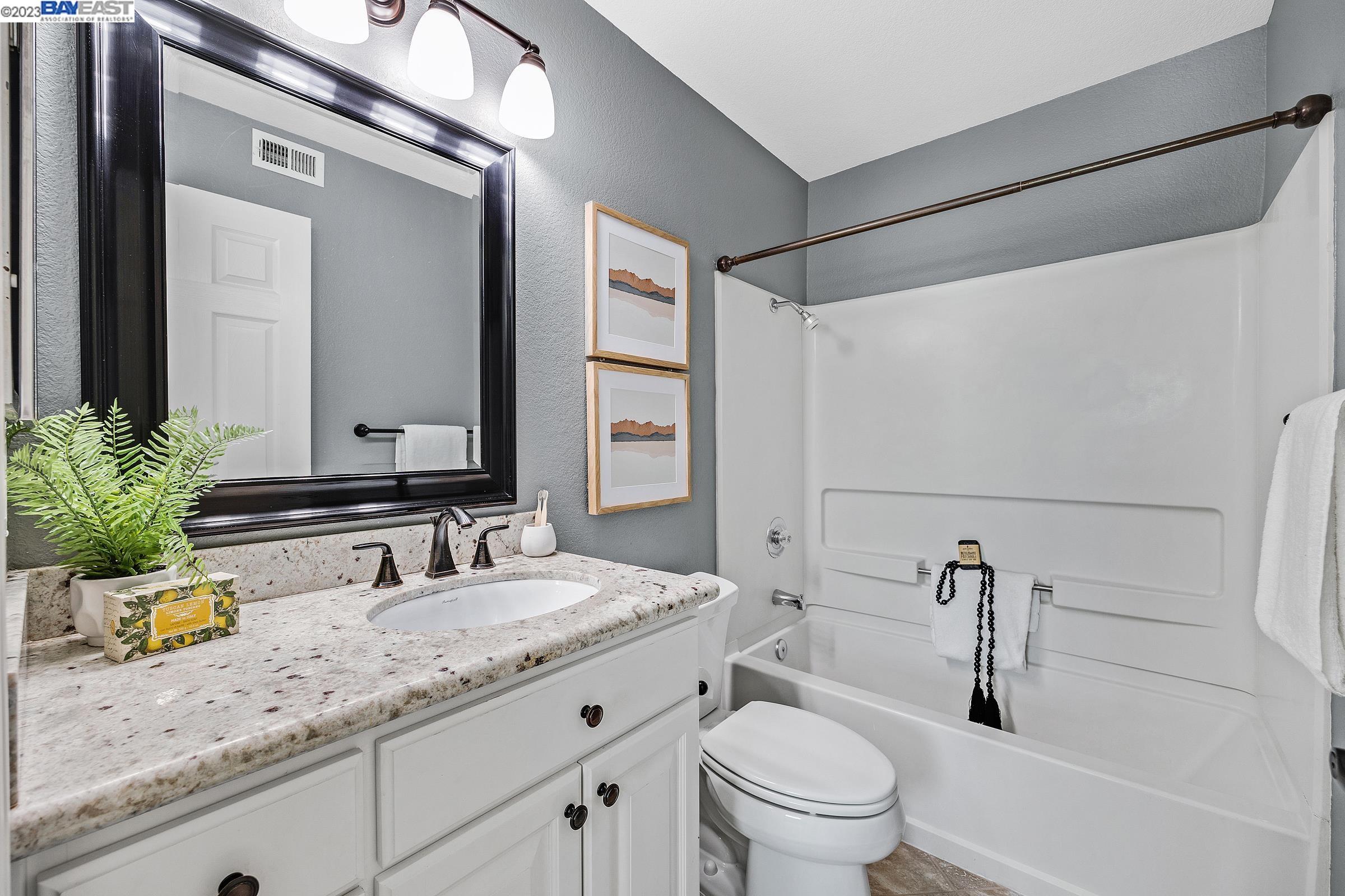 245 Reflections Drive San Ramon, CA 94583 - Photo 23 of 42 a bathroom with a granite countertop sink a toilet a mirror and shower