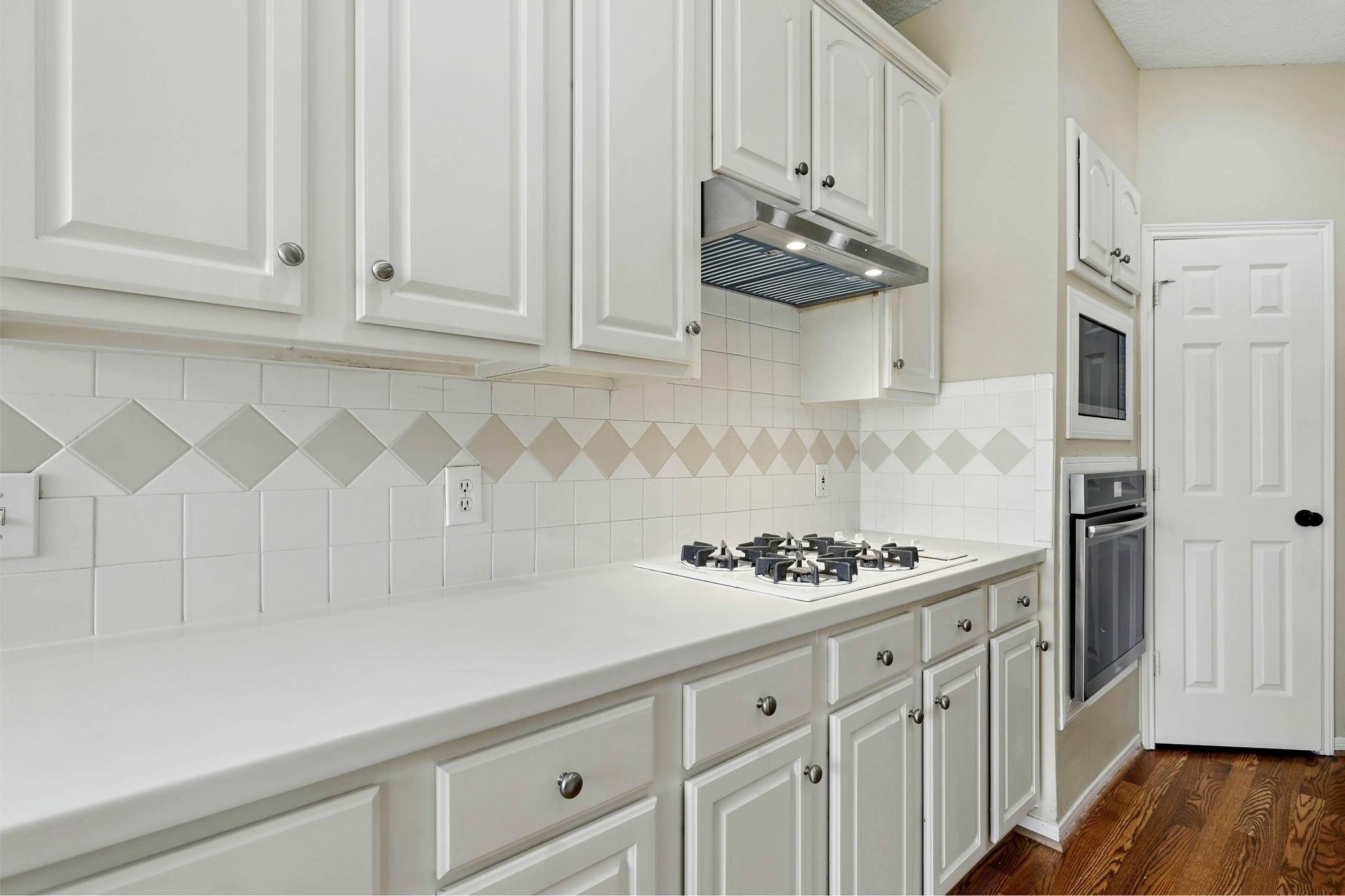 11030 Sprucedale Court Houston, TX 77070 - Photo 11 of 36 a kitchen with white cabinets and a stove