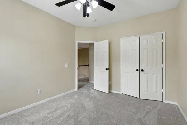 an empty room with closet and a ceiling fan