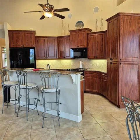 a kitchen with stainless steel appliances granite countertop a stove top oven a sink a dining table and chairs