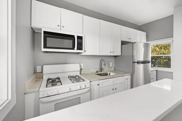 a kitchen with stainless steel appliances granite countertop a refrigerator sink stove and white cabinets