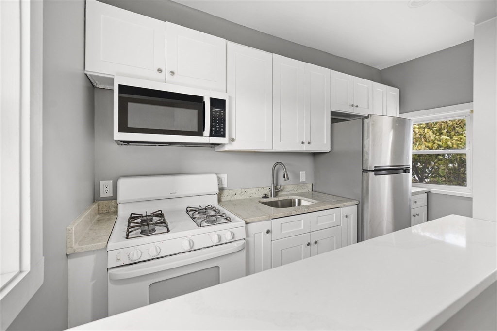 276 Washington Avenue, Unit 2 Chelsea, MA 02150 - Photo 5 of 28 a kitchen with stainless steel appliances granite countertop a refrigerator sink stove and white cabinets