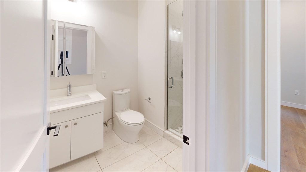16-18 Highgate Street, Unit 202 Boston, MA 02134 - Photo 13 of 14 a bathroom with a toilet a sink and a mirror
