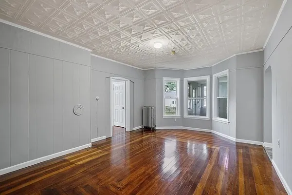 a view of a big room with wooden floor and windows