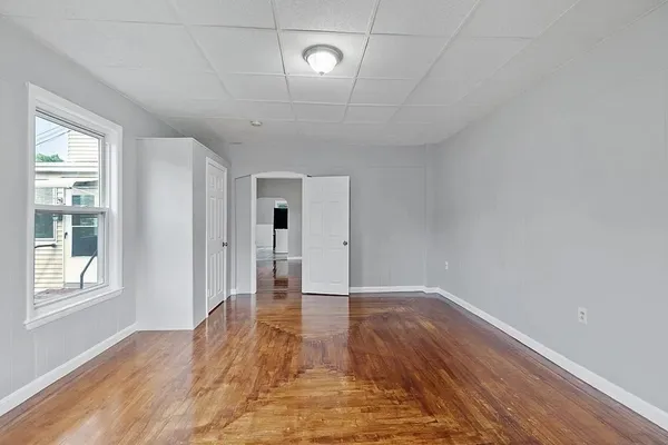 a view of an empty room with wooden floor and a window