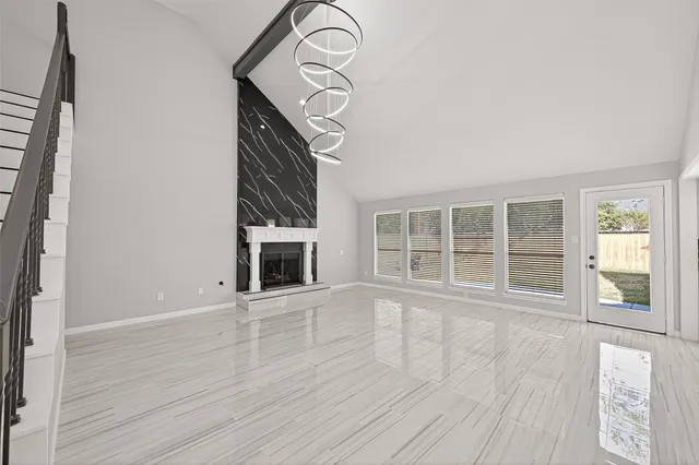 a view of an empty room with wooden floor and a fireplace