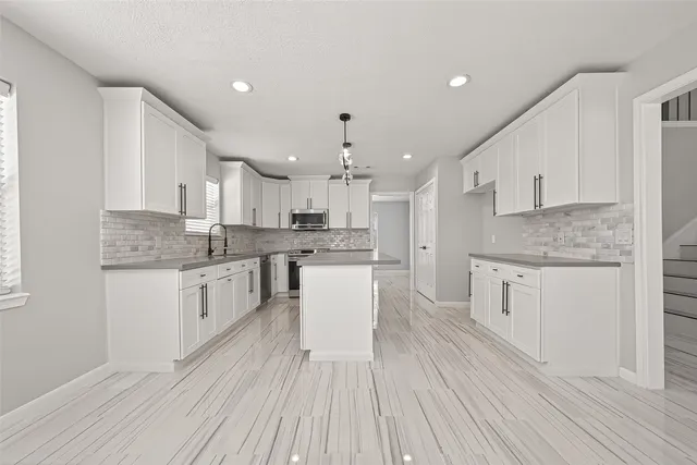 a kitchen with kitchen island granite countertop a sink cabinets and wooden floor