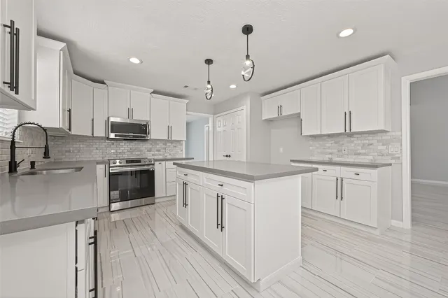 a kitchen with granite countertop white cabinets and stainless steel appliances