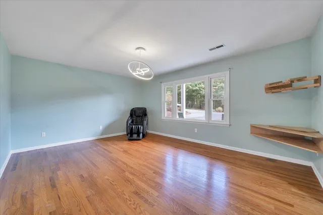 a view of an empty room with a window and wooden floor