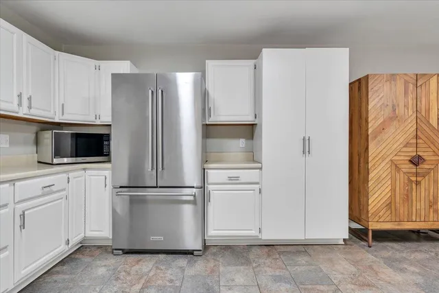 a kitchen with white cabinets appliances a sink and a window