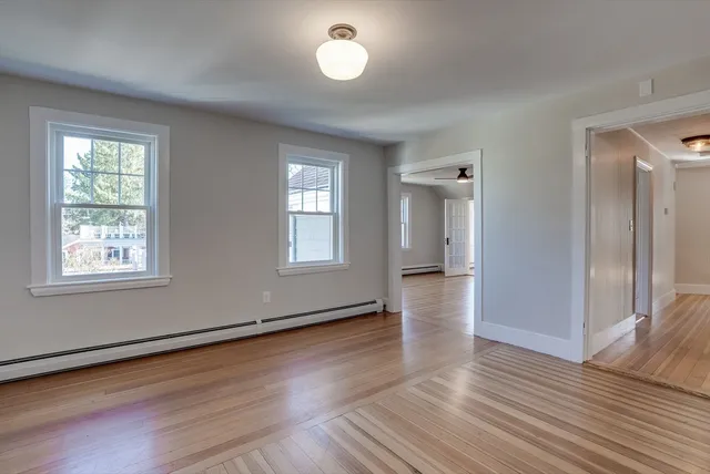 a view of an empty room with wooden floor and a window