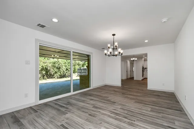 a view of a livingroom with a chandelier wooden floor and a window
