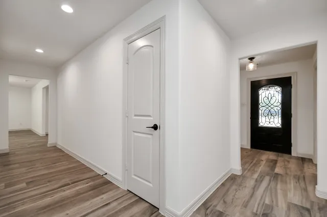 a view of a hallway with wooden floor and a bathroom
