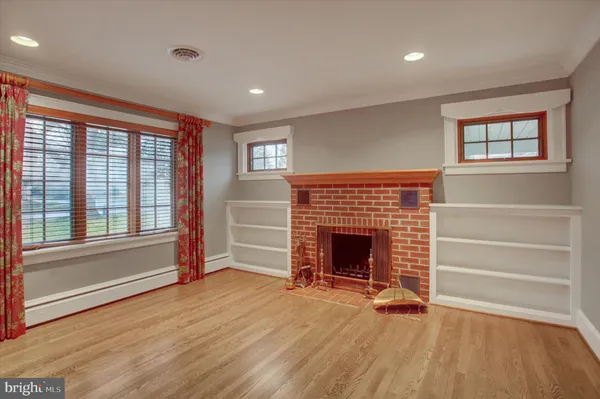 an empty room with wooden floor fireplace and windows