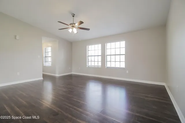 a view of an empty room with window and wooden floor