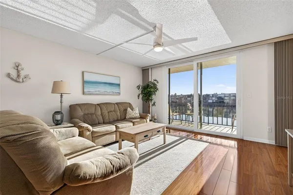 a living room with furniture large windows and wooden floor