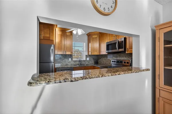 a kitchen with stainless steel appliances granite countertop a refrigerator a stove and a sink with granite countertops