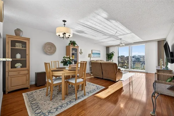 a dining room with wooden floor a chandelier a wooden table and chairs