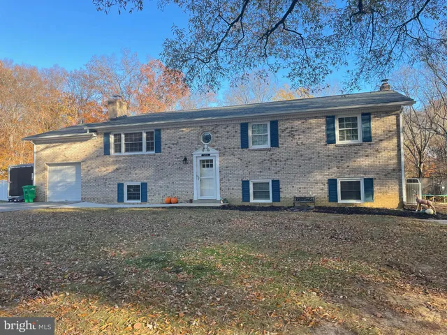 a view of a brick house next to a yard with large trees