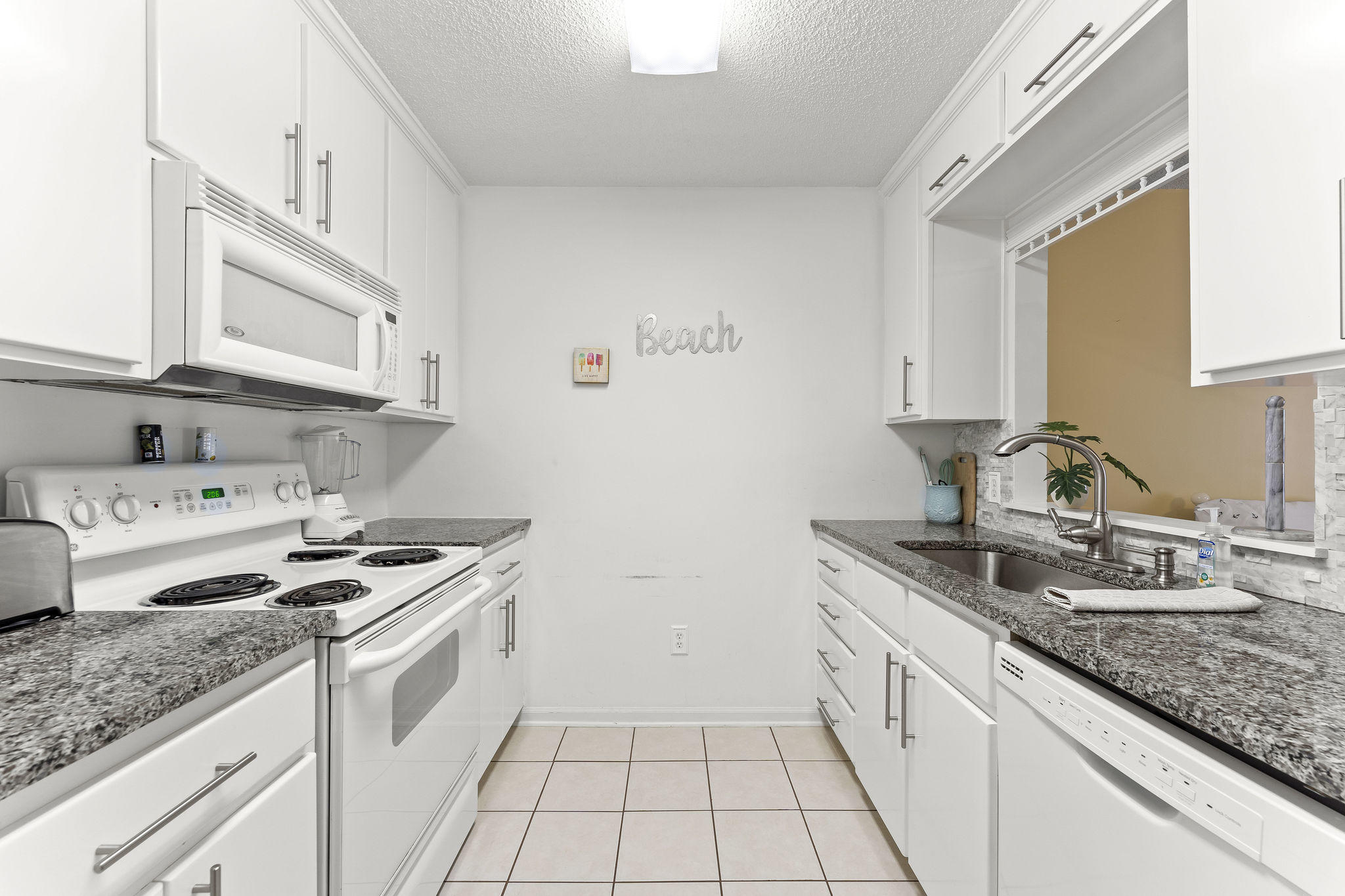 17462 Front Beach Road, Unit 77H Panama City Beach, FL 32413 - Photo 10 of 28 a kitchen with granite countertop a sink stove and cabinets