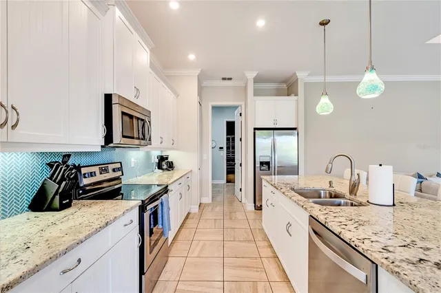 a kitchen with granite countertop a sink a counter top space appliances and cabinets