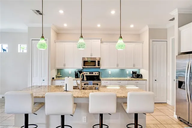 a kitchen with stainless steel appliances kitchen island granite top a refrigerator a stove a dining table and chairs