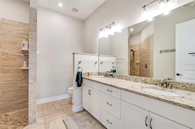 a bathroom with a granite countertop double vanity sink mirror and