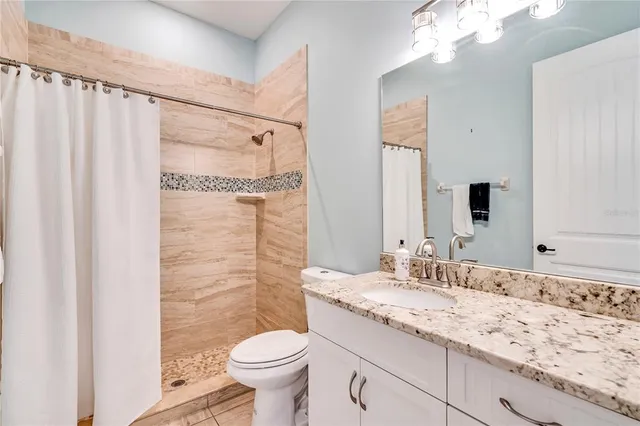 a bathroom with a granite countertop sink toilet and shower