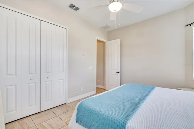 a bedroom with a large bed and a chandelier fan