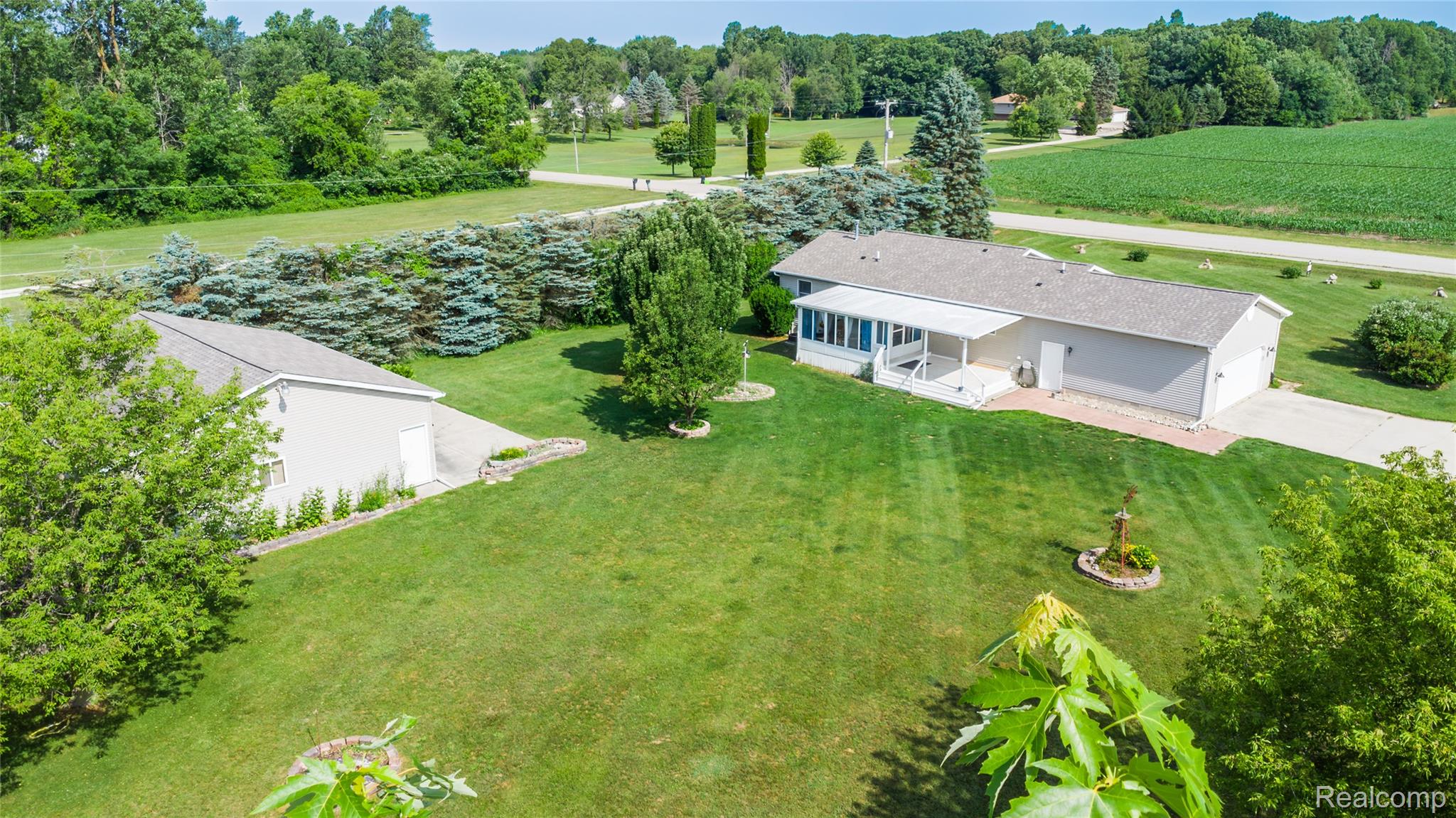 9600 Hamill Road Otisville, MI 48463 - Photo 3 of 32 Expansive property featuring a single-story residence with an attached garage, a detached auxiliary building, manicured lawns, mature evergreen trees, and a paved driveway