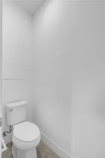 a white toilet sitting next to a white wall