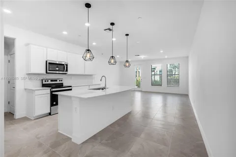 a large kitchen with granite countertop a stove a sink a window and chairs