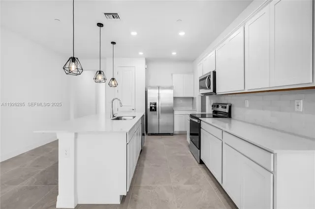 a kitchen with white cabinets and stainless steel appliances