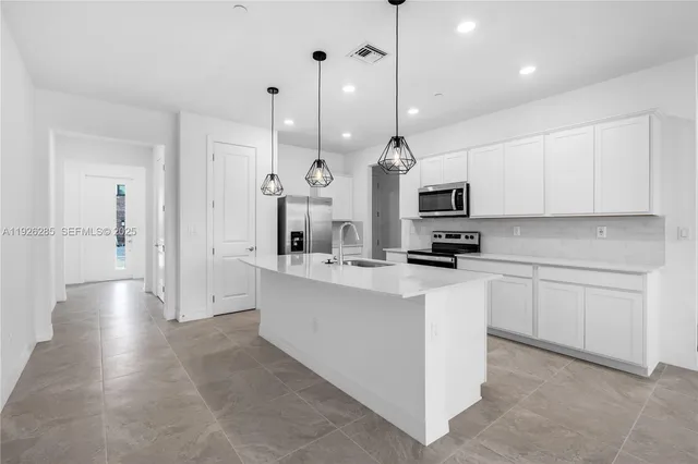 a kitchen with stainless steel appliances kitchen island granite countertop a sink a stove and a refrigerator