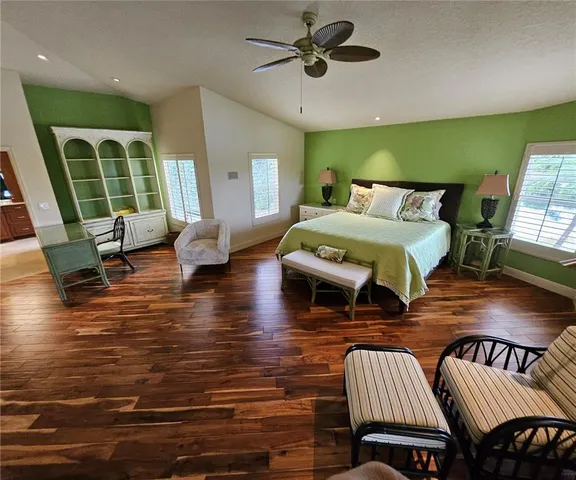 a bedroom with furniture wooden floor and a large window
