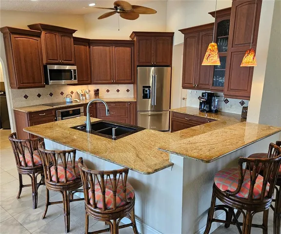 a kitchen with stainless steel appliances granite countertop a stove a refrigerator a microwave a sink and chairs