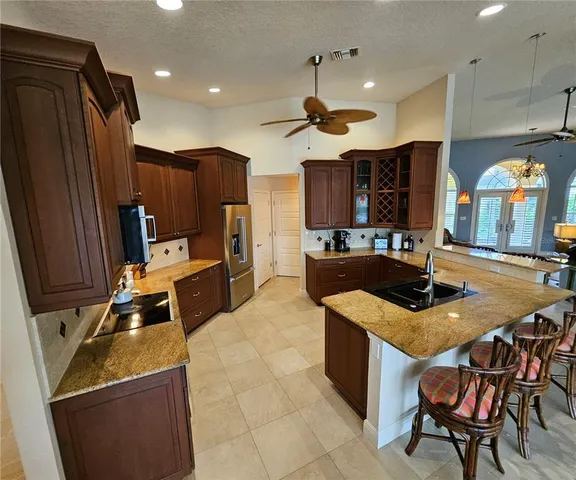 a kitchen with stainless steel appliances granite countertop a stove a refrigerator a sink a dining table and chairs with wooden floor