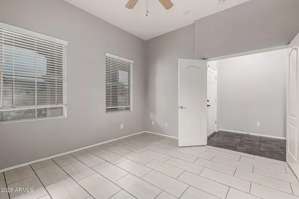 a view of an empty room with window and chandelier fan