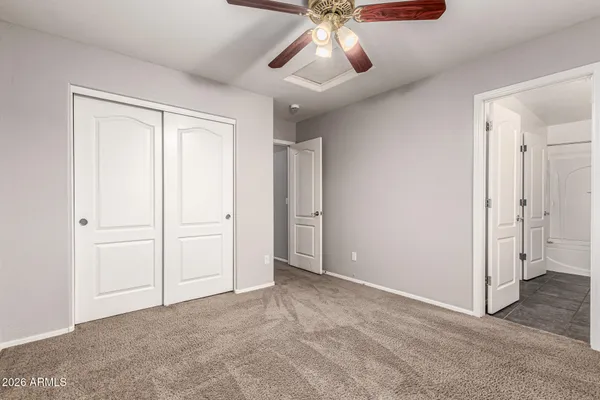 an empty room with closet and a chandelier fan