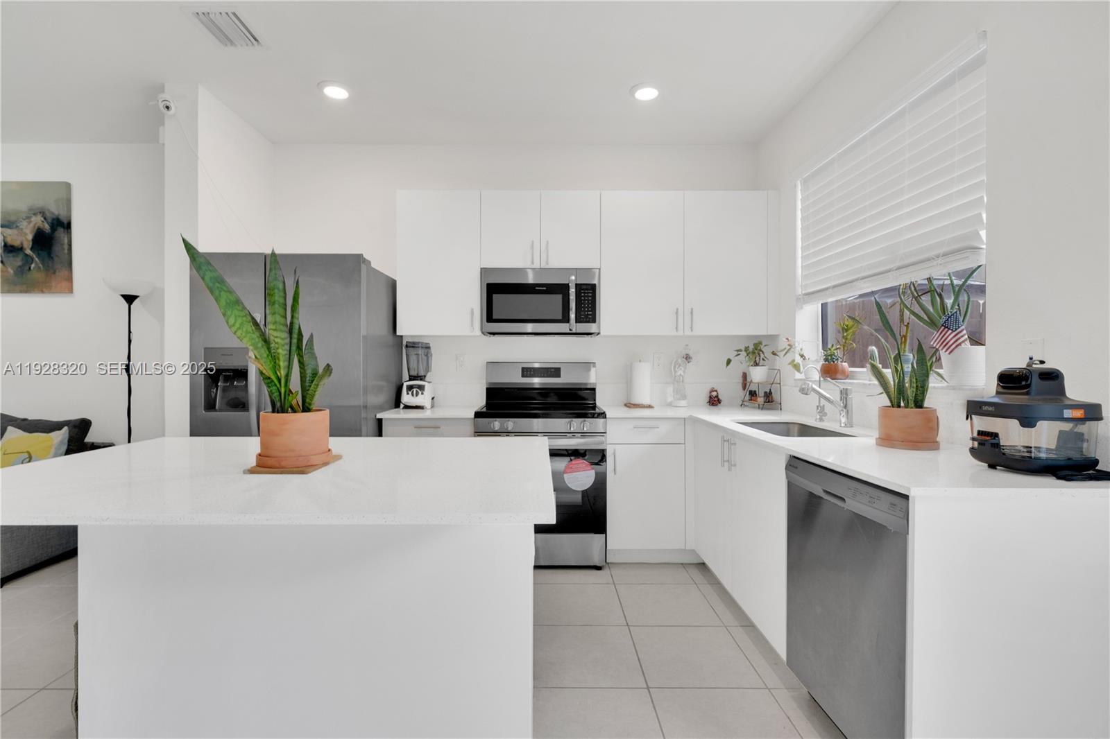 16266 Southwest 291st Street Homestead, FL 33033 - Photo 6 of 34 a kitchen with stainless steel appliances a stove a sink a microwave a refrigerator a sink and white cabinets