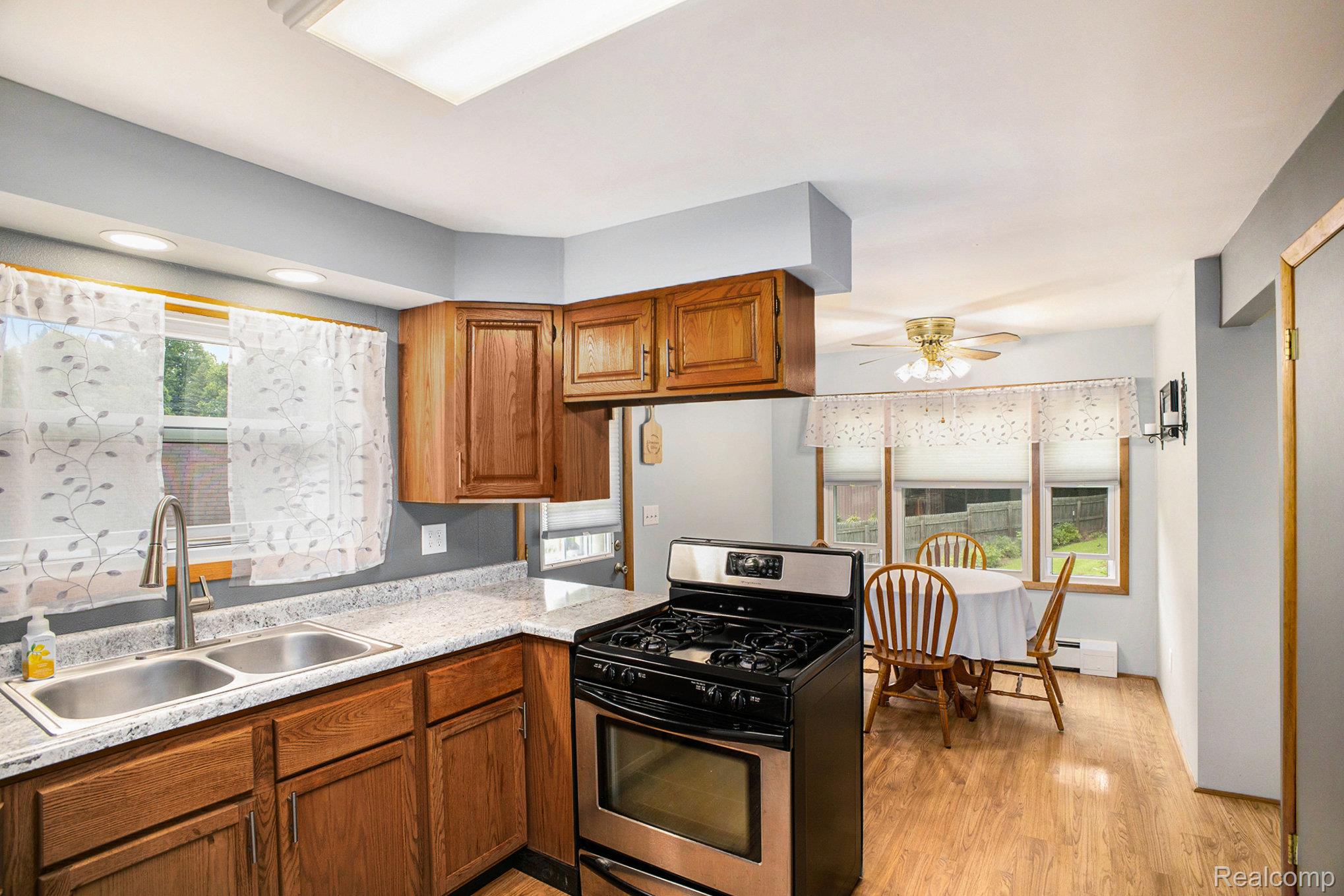 16568 28 Mile Road Albion, MI 49224 - Photo 7 of 26 Kitchen featuring stainless steel gas range oven, brown cabinetry, light wood-style flooring, light countertops, and ceiling fan