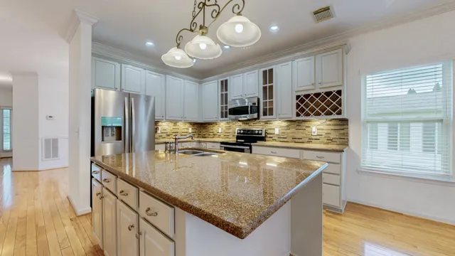 a kitchen with stainless steel appliances granite countertop a sink a stove and a refrigerator