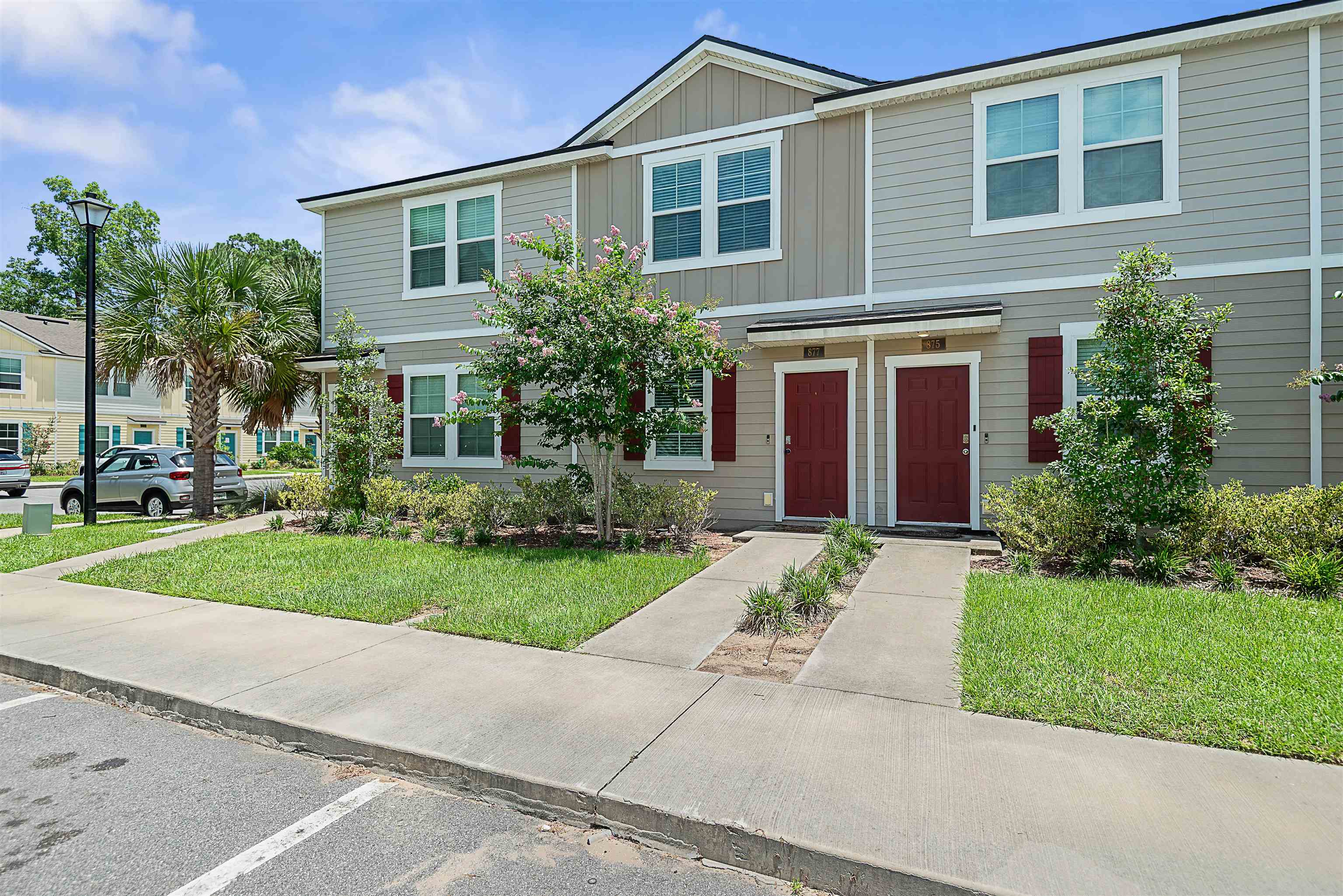 a front view of a house with a yard and potted plants
