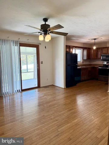 a view of a room with wooden floor ceiling fan and windows
