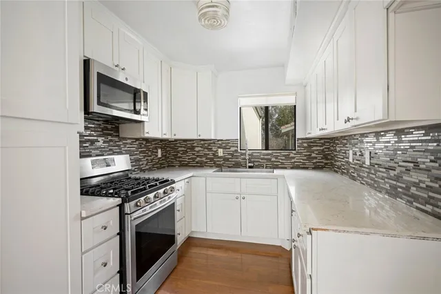 a kitchen with granite countertop a sink stove and microwave