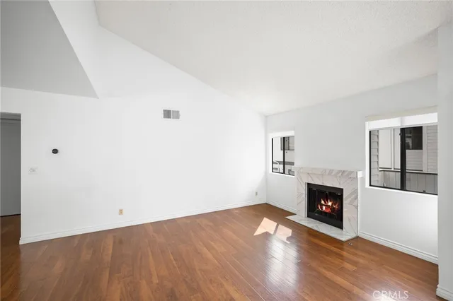 a view of empty room with wooden floor and fireplace