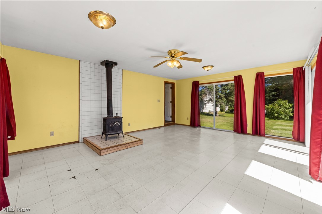 409 Edith Avenue Akron, OH 44312 - Photo 10 of 45 Spacious interior featuring a wood-burning stove on a raised tile hearth, multiple sliding glass doors, and light-toned tile flooring