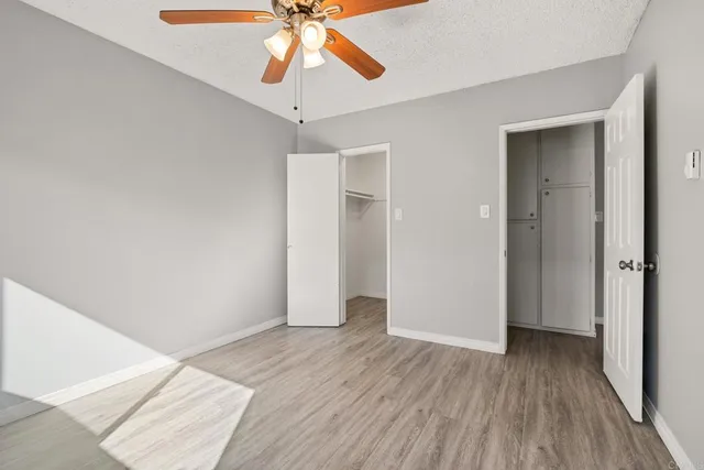 an empty room with wooden floor closet and chandelier fan