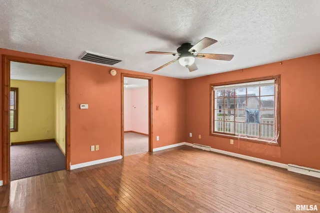 an empty room with wooden floor and windows