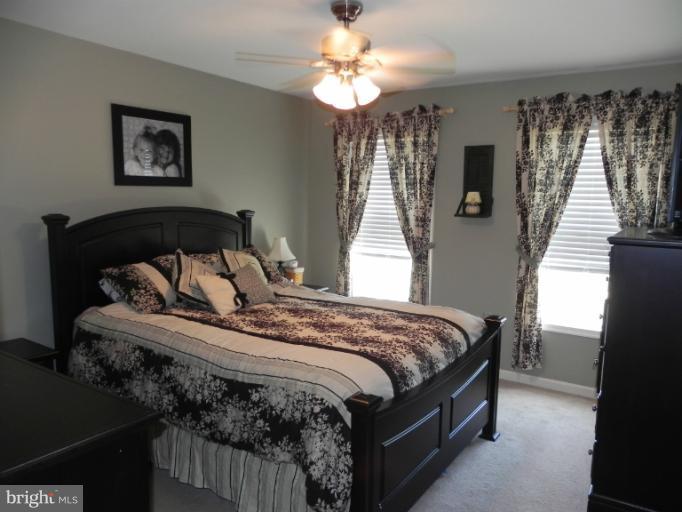 123 Quail Run Road Summit Point, WV 25446 - Photo 14 of 25 a bedroom with a bed and a chandelier